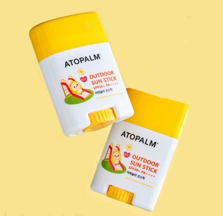 Two Atopalm outdoor sun stick containers on a yellow background